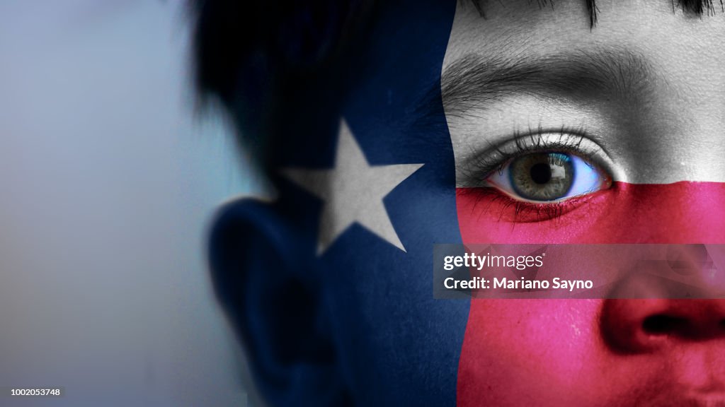 Boy's face, looking at camera, cropped view with digitally placed Texas State flag on his face.