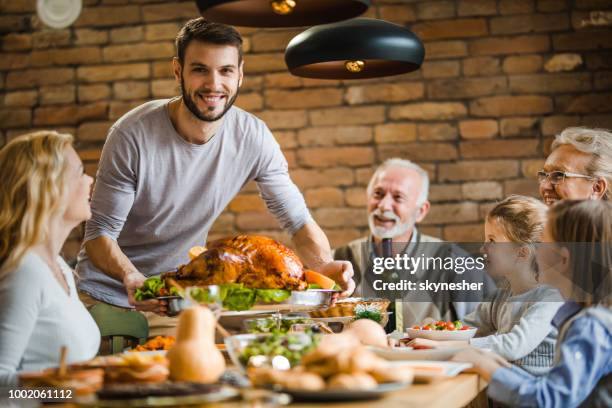 joven feliz sirviendo a su familia rellenos de pavo en la cena de acción de gracias en la mesa de comedor. - christmas turkey fotografías e imágenes de stock