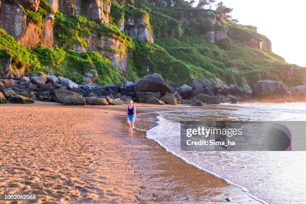 mature woman walking along the coast - asturias stock pictures, royalty-free photos & images