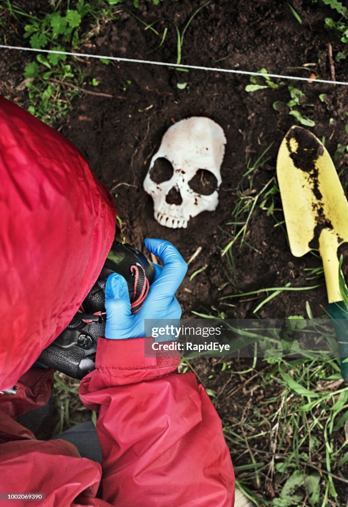 Escena de crimen investigador fotografiando desenterrados cráneo humano