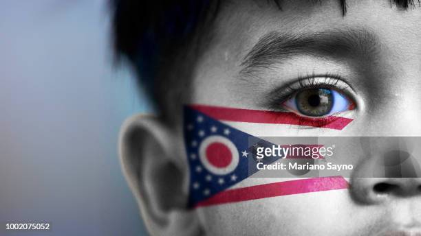 boy's face, looking at camera, cropped view with digitally placed ohio state flag on his face. - columbus government stockfoto's en -beelden