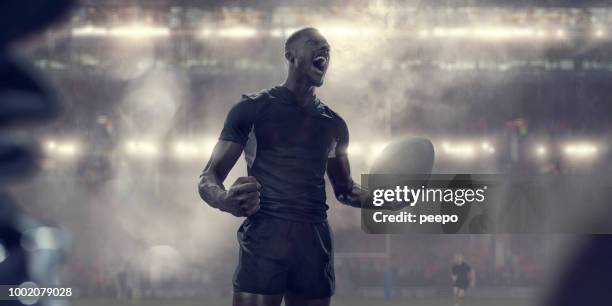 rugby player in black kit holding ball shouting in celebration - rugby union ball stock pictures, royalty-free photos & images