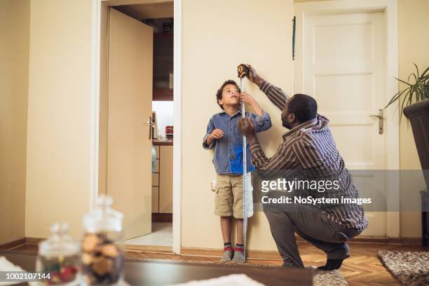 father measuring sons height - fathers day tools stock pictures, royalty-free photos & images