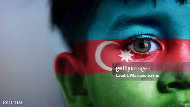 boy's face, looking at camera, cropped view with digitally placed azerbaijan flag on his face. - azerbaijan stockfoto's en -beelden