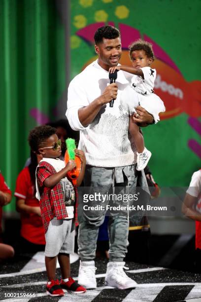 Player Russell Wilson accepts the Best Cannon award with Future Zahir Wilburn and Sienna Princess Wilson onstage during the Nickelodeon Kids' Choice...