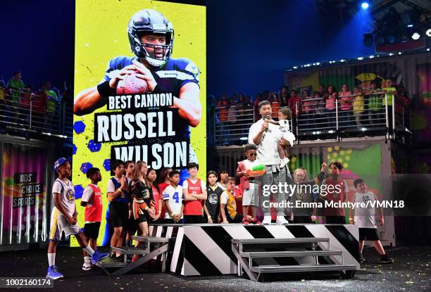 Player Russell Wilson accepts the Best Cannon award with Future Zahir Wilburn and Sienna Princess Wilson onstage during the Nickelodeon Kids' Choice...