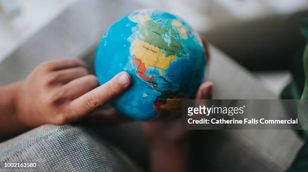 child pointing to a globe - emigration and immigration stock pictures, royalty-free photos & images