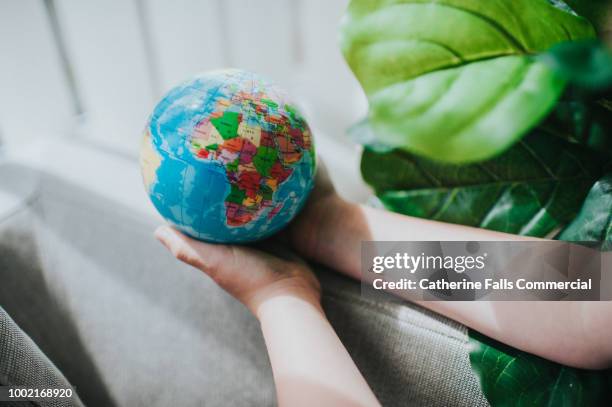 childs hand holding a globe - algeria demonstrations stock pictures, royalty-free photos & images