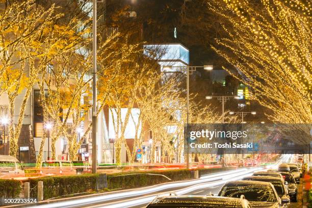 cars go through among the illuminated tree lined omotesadndo street for winter holydays season in the night at kitaaoyama, minato tokyo japan on december 06 2017. - omotesando tokio stockfoto's en -beelden