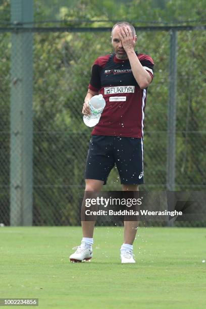 Andres Iniesta of Vissel Kobe tries to cool himself with a bottle of water during break of training season as temperature has hit 36 C, while his...