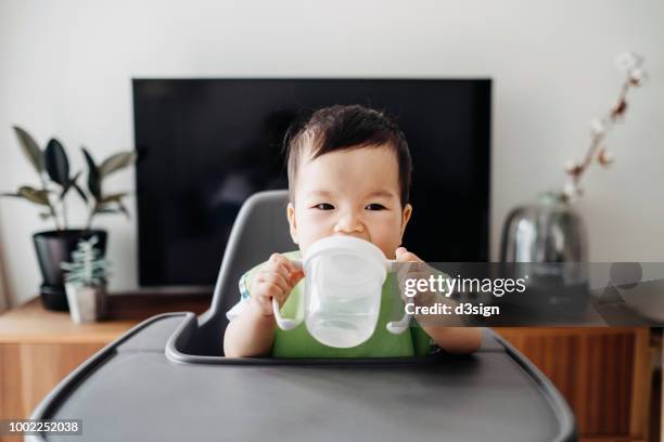 cute baby drinking water from sip cup on high chair - caneca para bebê - fotografias e filmes do acervo