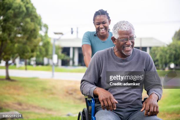 senior black man in wheelchair with daughter - medical partnership stock pictures, royalty-free photos & images