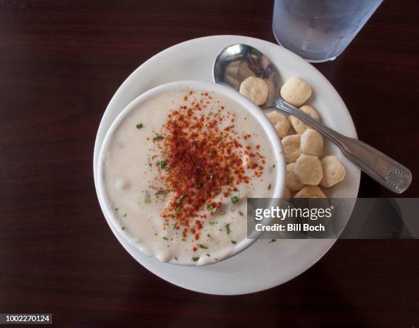 cup of clam chowder with crackers and iced water at a seafood restaurant - new england clam chowder stock-fotos und bilder