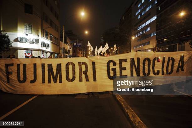 Demonstrators march while hold a banner reading "Fujimori Genocida" during a protest demanding judicial reforms and accountability for corrupt judges...