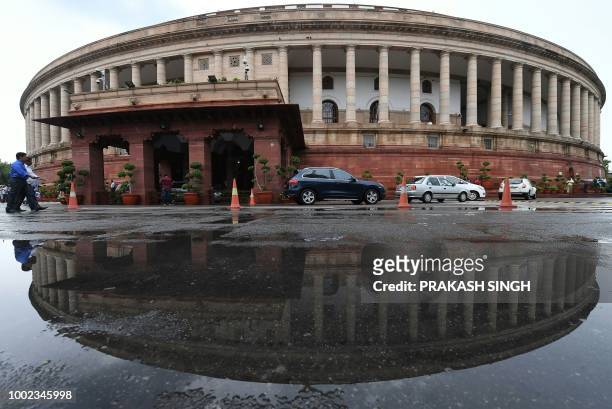 The Indian Parliament building is reflected in a puddle after heavy rain during the monsoon session of the Indian Parliament in New Delhi on July 20,...