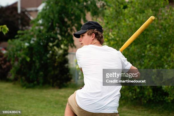 adolescente che gioca a baseball nel parco dei sobborghi. - batting foto e immagini stock
