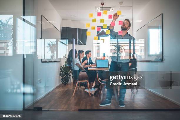 web designer sticking adhesive note on glass wall - webdesigner stock pictures, royalty-free photos & images