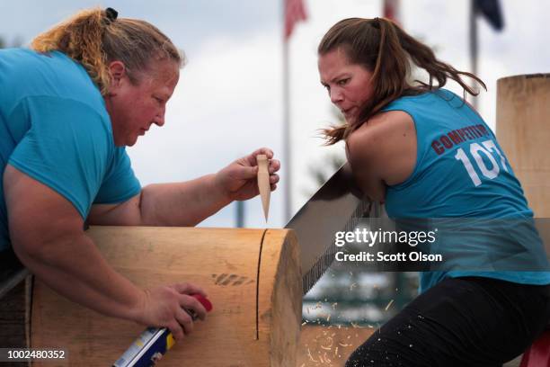With the help of Nancy Zalewski of Manitowoc, Wisconsin, Kendal Kunelius from Chester, New Hampshire competes in the Single Buck sawing event at the...