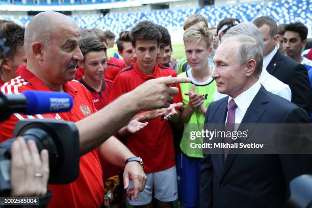 Russian President Vladimir Putin listens to national football team coach Stanislav Cherchesov during their meeting in on the field of Kaliningrad...