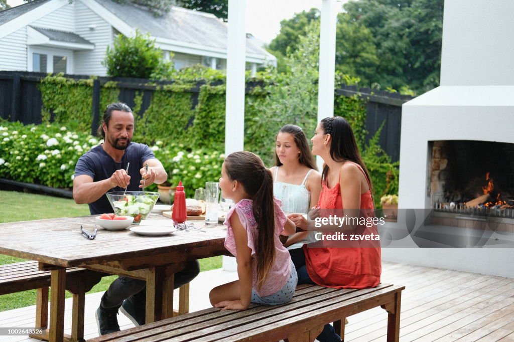 Family of four enjoying summer lunch on their outdoor patio at home