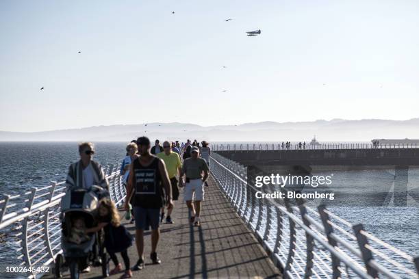 Pedestrians walk along the Ogden Point Breakwater walkway in Victoria, British Columbia, Canada, on Friday, July 13, 2018. Canadian tourism spending...