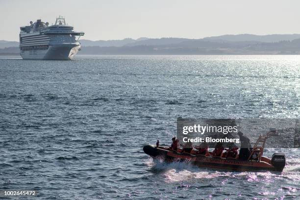 Whale watching boat passes in front of a cruise ship traveling towards the Ogden Point Cruise Terminal in Victoria, British Columbia, Canada, on...