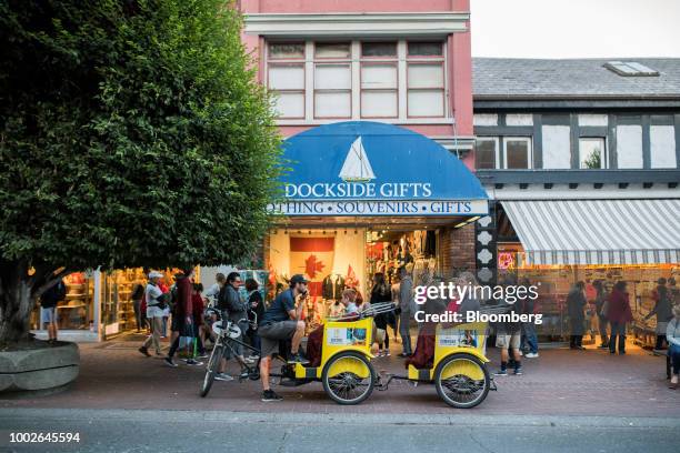 Bicycle rickshaw driver speaks to passengers in front of a souvenir store in downtown Victoria, British Columbia, Canada, on Friday, July 13, 2018....