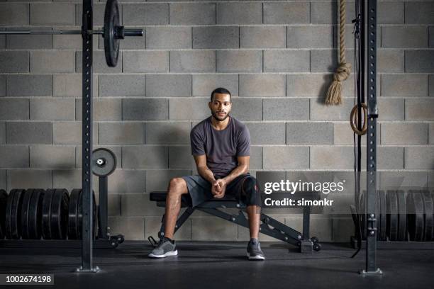 young man sitting on bench press - tee sports equipment stock pictures, royalty-free photos & images