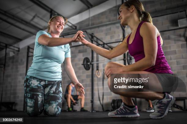 instructor holding hand of woman in gym - pink shirt stock pictures, royalty-free photos & images