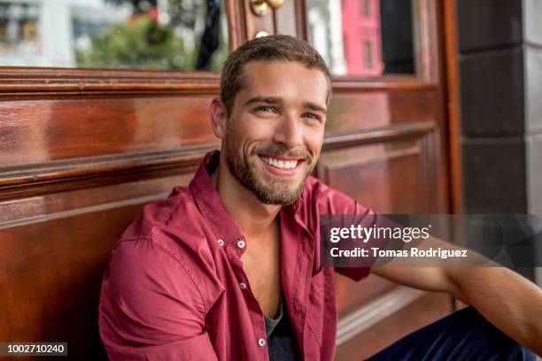 portrait of smiling young man at the door - knappe man stockfoto's en -beelden