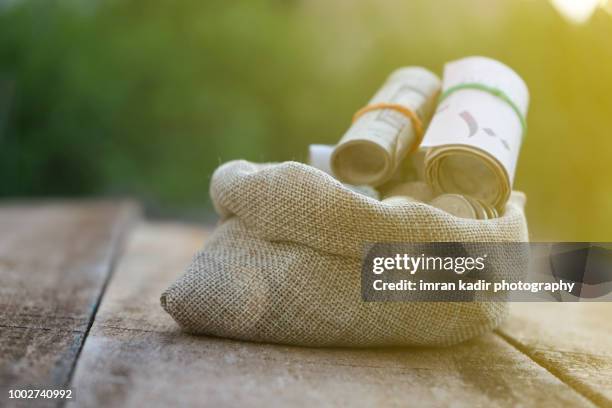 saudi riyal in sacks bag on the wooden table - islamic finance stock pictures, royalty-free photos & images