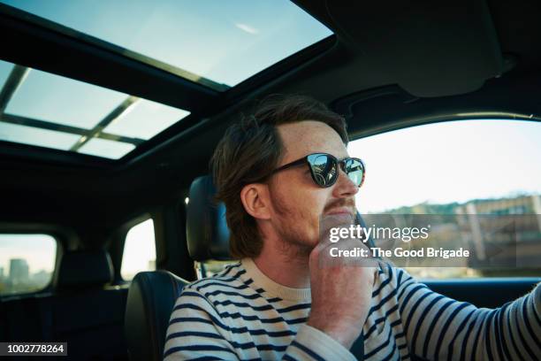 young man driving car on sunny day - soltak bildbanksfoton och bilder