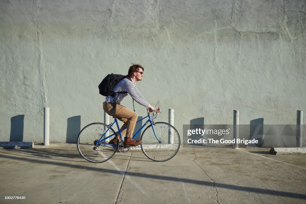 Businessman riding bicycle along concrete wall