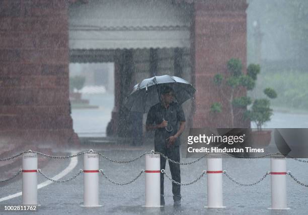 Narendra Modi's security guard stands with an umbrella as it rains during the third day of the Monsoon Session of Parliament on July 20, 2018 in New...