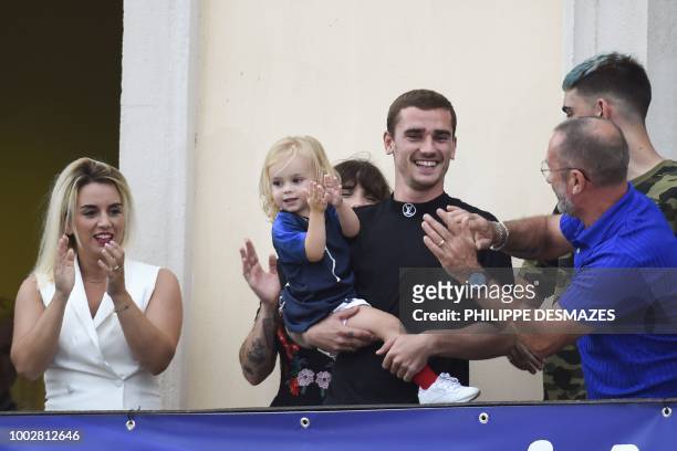 French football player Antoine Griezmann holds his daughter Mia as he celebrates with his wife Erika and father Alain in his hometown of Macon,...