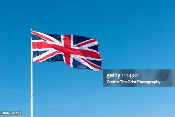 union jack flag of great britain against a blue sky - bandiera del regno unito foto e immagini stock