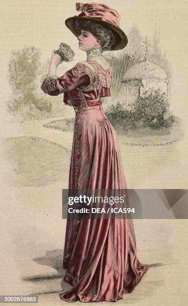 Woman wearing an antique pink satin afternoon dress, pleated skirt, corset embroidered with tone on tone braids and a hat with ribbon, creation by...