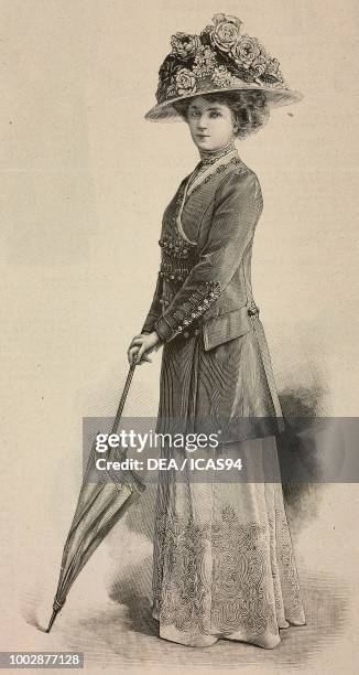 Woman wearing a walking dress, wide embroidered skirt, long jacket and a hat with flowers, creation by Drecoll, engraving from La Mode Illustree, No...