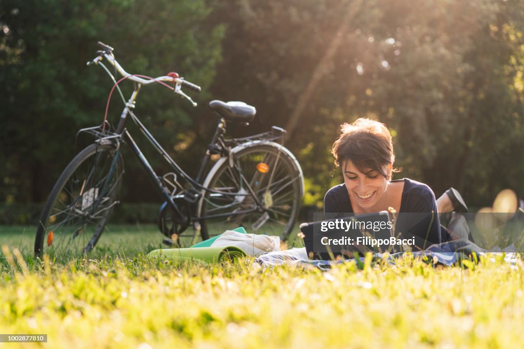 Adulta jovem ler um ebook em um parque público