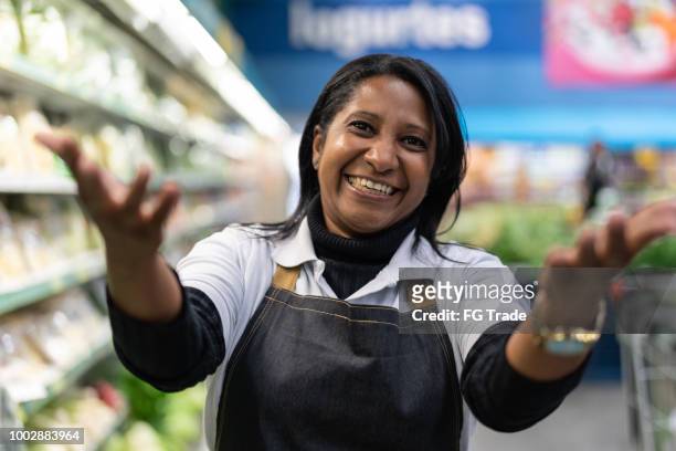 supermarket employee woman beckoning - inviting clients to come - beckoning stock pictures, royalty-free photos & images