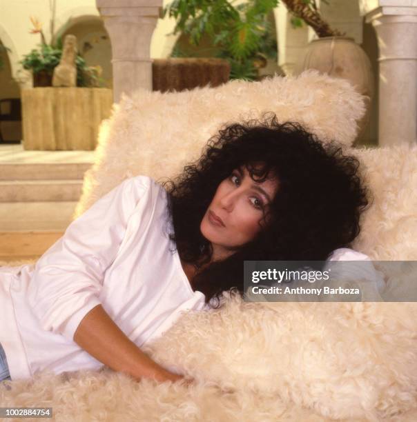 Portrait of American singer and actress Cher as she lies on a fuzzy couch, Los Angeles, California, 1987. .