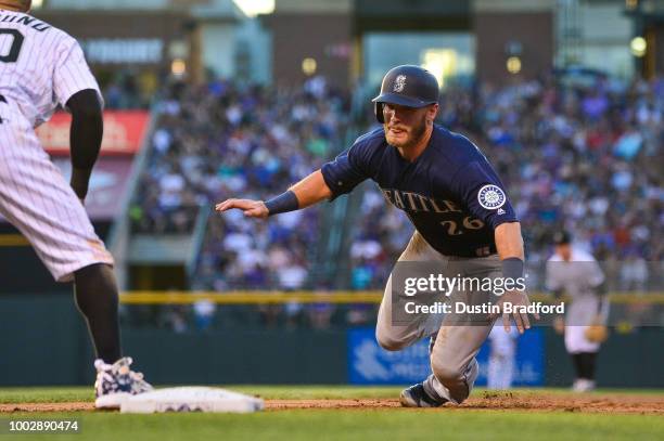 Chris Herrmann of the Seattle Mariners dives back to first base to avoid a pickoff during a game at Coors Field on July 14, 2018 in Denver, Colorado.