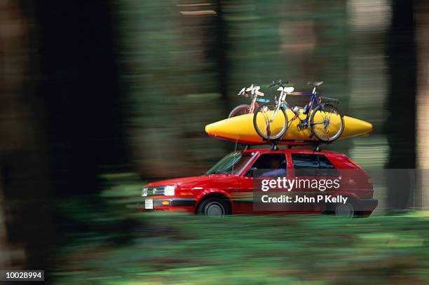 red car with kayak driving in forest - carrying kayak stock pictures, royalty-free photos & images