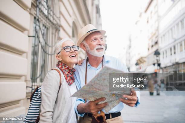 senior couple holding a map and looking at distance - elderly couple holiday stock pictures, royalty-free photos & images