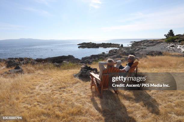 couple relax on wooden chair, look out to calm sea - victoria canada stock-fotos und bilder