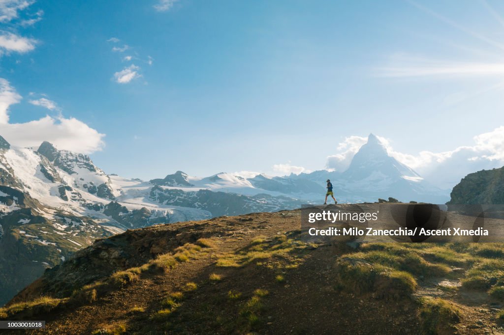 Male trail runner ascends above glaciated landscape