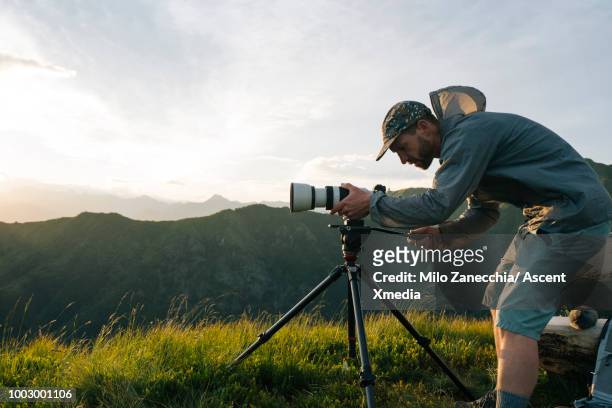 photographer takes pics at sunrise, on mountain top - photographer stock-fotos und bilder