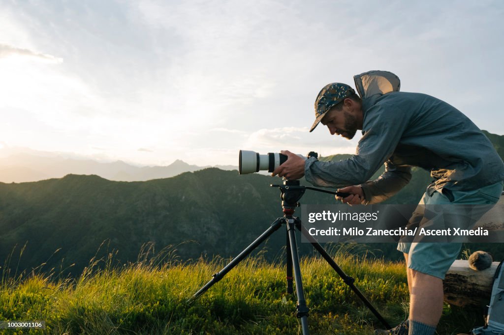 Photographer takes pics at sunrise, on mountain top