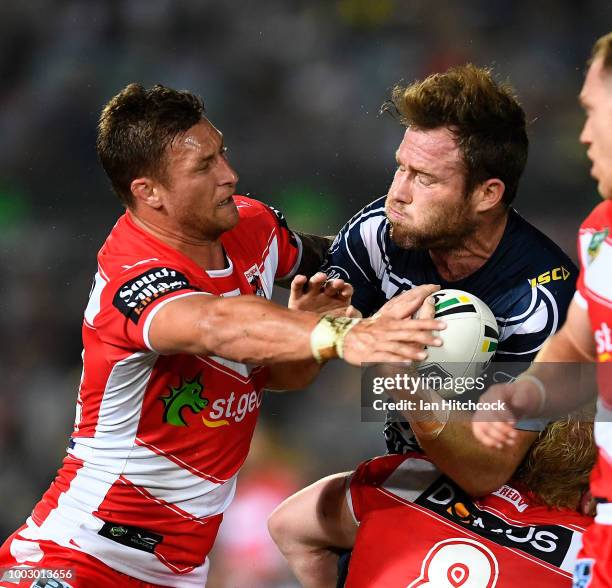 Gavin Cooper of the Cowboys is tackled by Tariq Sims of the Dragons during the round 19 NRL match between the North Queensland Cowboys and the St...