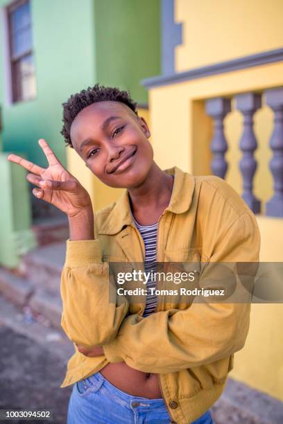 portrait of a confident young woman making victory hand sign outdoors - victory sign stock-fotos und bilder